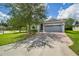 Charming single-story home with a manicured lawn, mature trees, and a brick-paved driveway leading to a two-car garage at 3604 Corsica Ln, Clermont, FL 34711