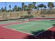 Well-maintained tennis courts with green and red surface surrounded by lush landscaping and mature trees at 3604 Corsica Ln, Clermont, FL 34711