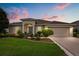 Attractive single-story home featuring a well-kept lawn and flowerbeds under a colorful sunset sky at 4210 Arlington Ridge Blvd, Leesburg, FL 34748