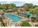 Aerial view of a resort-style pool area featuring a lap pool, free-form pool, pergolas, and lounge chairs at 4210 Arlington Ridge Blvd, Leesburg, FL 34748
