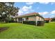Spacious backyard with lush grass and home exterior with a tile roof at 5071 Harbour Dr, Oxford, FL 34484
