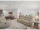 Open-concept living room features neutral tones, ceiling fan, and seamless flow to kitchen and dining areas at 5719 Spartina Ter, The Villages, FL 32163