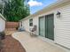 A quaint backyard area with a concrete patio, chair, sliding glass door, and manicured landscaping at 5719 Spartina Ter, The Villages, FL 32163