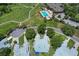 Aerial view of a home near a golf course, pool, and clubhouse, nestled within a lush, green landscape at 6036 Topsail Rd, Lady Lake, FL 32159
