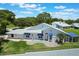 Aerial view of a single-story home featuring blue awnings, green grass, and a screened-in lanai at 6036 Topsail Rd, Lady Lake, FL 32159