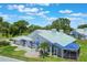 Aerial view of home with blue awnings, blue roof tiles, a screened in lanai and lush green lawn at 6036 Topsail Rd, Lady Lake, FL 32159