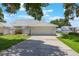 Attached two-car garage with a white door and tile roof, set within a well-maintained lawn and garden landscape at 6036 Topsail Rd, Lady Lake, FL 32159