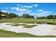 Scenic golf course view showcasing lush green fairways, a sand trap, and water features under a bright blue sky at 6036 Topsail Rd, Lady Lake, FL 32159