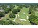 Aerial view of a golf course featuring tree-lined fairways, sand traps, and pristine green spaces in a community at 6036 Topsail Rd, Lady Lake, FL 32159