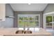 Bright kitchen with stainless steel sink, granite counters, and views of the green space through shuttered windows at 6036 Topsail Rd, Lady Lake, FL 32159