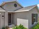 Exterior angle showing tan stucco and a dark front door, complete with a circle vent and window with shutters at 6946 Perch Hammock Loop, Groveland, FL 34736
