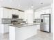 Modern kitchen with stainless steel appliances, gray tile backsplash, and a center island at 6946 Perch Hammock Loop, Groveland, FL 34736