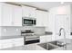 Modern kitchen featuring stainless steel appliances, gray backsplash, and a double sink at 6946 Perch Hammock Loop, Groveland, FL 34736