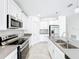 Bright kitchen features white cabinets, stainless steel appliances, and stone countertops at 6946 Perch Hammock Loop, Groveland, FL 34736