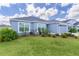 Charming single Gathering home with lush green lawn, mature plantings and attached two car garage on a sunny day at 6949 Minchew Cir, The Villages, FL 34762