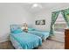 Bright bedroom with two twin beds and tropical themed decor at 703 Royal Palm Ave, Lady Lake, FL 32159