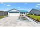 Charming single-story home with blue awnings, an attached garage, and a beautifully landscaped front yard at 714 Prado Dr, The Villages, FL 32159