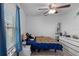 Comfortable bedroom featuring a ceiling fan, large window with blue curtains, and warm lighting at 7901 Iceland Gull St, Winter Garden, FL 34787