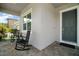 Inviting front porch featuring rocking chairs, a small table, and a gray brick floor at 9153 Carmela Ave, Davenport, FL 33897