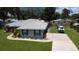 Aerial view of the home with gray roof, double driveway, manicured lawn, and green surrounding landscape at 1007 Cr 463B, Lake Panasoffkee, FL 33538