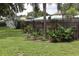 Lush backyard features a mix of tropical plants, a wood fence, and an open grassy space at 1007 Cr 463B, Lake Panasoffkee, FL 33538