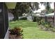 Well-maintained backyard with mature trees, manicured lawn, patio seating, and vibrant landscaping at 1007 Cr 463B, Lake Panasoffkee, FL 33538