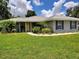 Charming single-story home with well-manicured lawn, lush landscaping, and a welcoming yellow front door at 1007 Cr 463B, Lake Panasoffkee, FL 33538