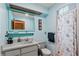 Light blue bathroom with tiled shower, a framed mirror, and a white vanity sink at 1048 Cr 452A, Lake Panasoffkee, FL 33538