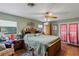 Spacious bedroom showcasing a large bed, ceiling fan, and natural light from windows and patio doors at 1048 Cr 452A, Lake Panasoffkee, FL 33538