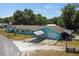 Aerial view of a well-maintained turquoise house with a large driveway and mature trees in the background at 1048 Cr 452A, Lake Panasoffkee, FL 33538