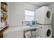 Functional laundry room featuring a stacked washer and dryer, storage shelves, and ample counter space for folding at 1048 Cr 452A, Lake Panasoffkee, FL 33538