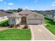 Inviting single-story home featuring a beige exterior, well-manicured lawn, and an attached two-car garage at 10927 Se 168Th Loop, Summerfield, FL 34491