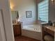 Bathroom showcasing a corner tub with glass block window and granite countertop vanity at 12183 Se 178Th St, Summerfield, FL 34491