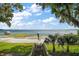 Backyard view of stairs going down to a lake with a sandy beach, docks, and palm trees at 13033 Se 158Th Ln, Weirsdale, FL 32195