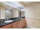 Bathroom featuring dual sinks with black countertops and wood cabinets, plus a large mirror and step-in shower at 13033 Se 158Th Ln, Weirsdale, FL 32195
