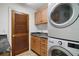 Functional laundry room with stackable washer/dryer, granite countertops, and wood-slat door at 13033 Se 158Th Ln, Weirsdale, FL 32195