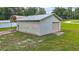 Small outbuilding with white siding and trim, and a metal roof, surrounded by green grass at 13033 Se 158Th Ln, Weirsdale, FL 32195
