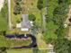Aerial view of the property featuring a home with a pond, dock, and a spacious yard, set in a tranquil, wooded area at 135 N James Pl, Groveland, FL 34736