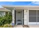Close-up of the front entrance featuring a storm door, ADT security system, and well-manicured shrubs at 135 N James Pl, Groveland, FL 34736