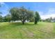 Expansive front yard featuring a mature weeping willow tree, providing ample shade and curb appeal at 135 N James Pl, Groveland, FL 34736