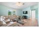 Comfortable living room featuring a neutral sectional sofa, contemporary glass table, and wood laminate floors at 135 N James Pl, Groveland, FL 34736