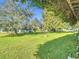 Lush green backyard featuring a well-manicured lawn, mature trees, and glimpses of the home's exterior, perfect for outdoor activities at 13700 Se 90Th Ct, Summerfield, FL 34491