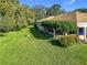 Expansive backyard with a well-maintained lawn, mature trees, and a covered patio area at 13700 Se 90Th Ct, Summerfield, FL 34491