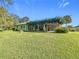 Expansive backyard view showcasing a spacious lawn, mature trees, and the home's covered patio, ideal for outdoor living at 13700 Se 90Th Ct, Summerfield, FL 34491