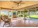 Relaxing covered patio featuring comfortable seating, an overhead fan, and views of the lush, well-maintained backyard at 13700 Se 90Th Ct, Summerfield, FL 34491