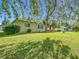 Charming home exterior with a lush green lawn, mature trees, and a welcoming covered patio, perfect for enjoying the outdoors at 13700 Se 90Th Ct, Summerfield, FL 34491