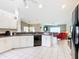 Bright kitchen featuring white cabinets, black appliances, with an open concept to the living area at 13700 Se 90Th Ct, Summerfield, FL 34491