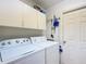 Functional laundry room with white washer and dryer, complemented by ample overhead cabinet space for organized storage at 13700 Se 90Th Ct, Summerfield, FL 34491