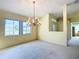 Living room with chandelier, bright walls, neutral carpeting, and large windows filling the room with light at 13700 Se 90Th Ct, Summerfield, FL 34491