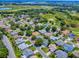 Aerial view of houses in a neighborhood with mature trees and a golf course in the background at 1419 Arbor Trl, The Villages, FL 32162